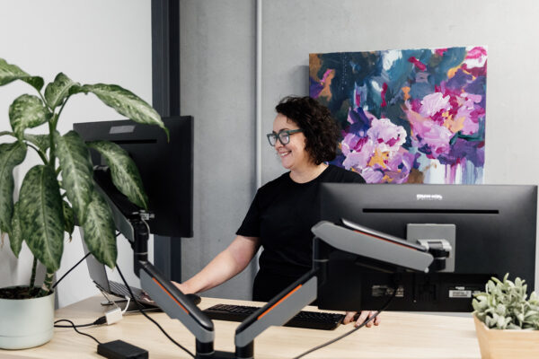 Julia Fiore of Seed People Consulting working at her dual-monitor workstation — an example of a well-designed role and work environment.